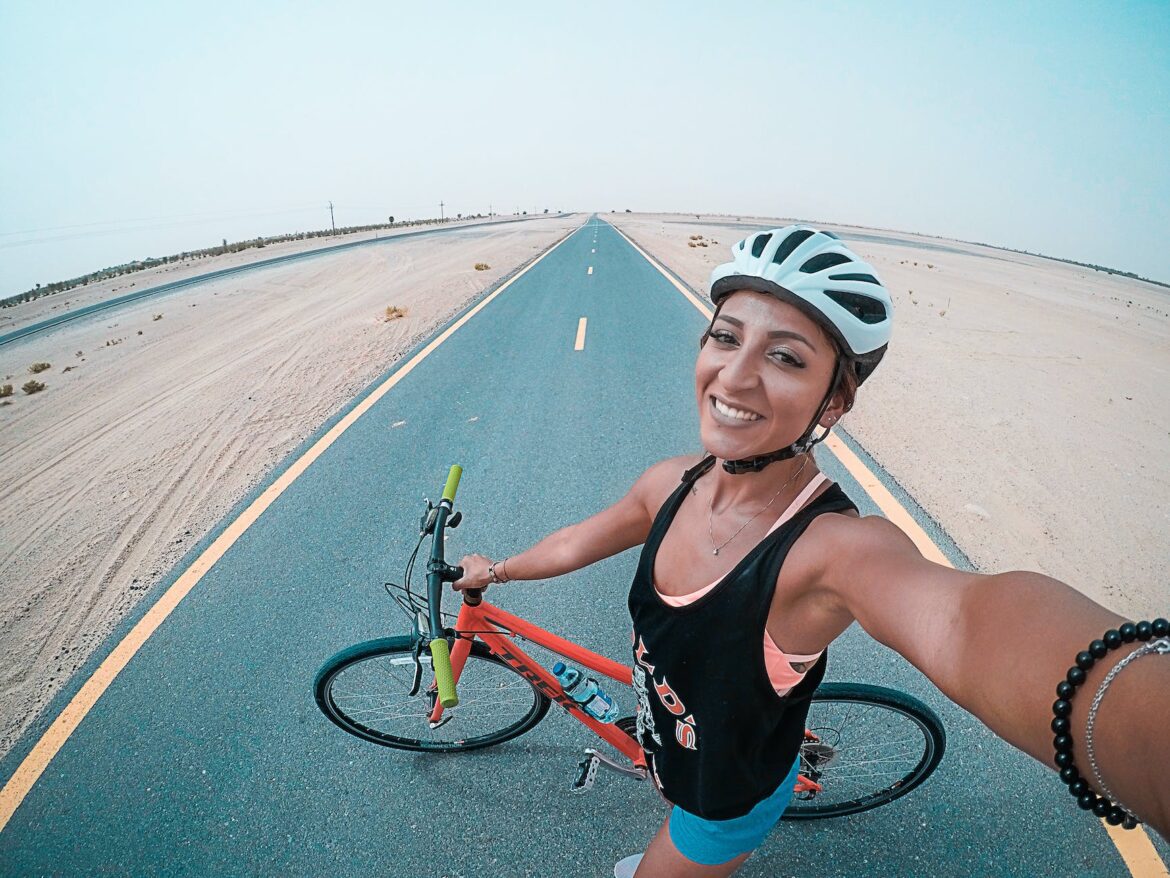 woman holding bicycle on asphalt road
