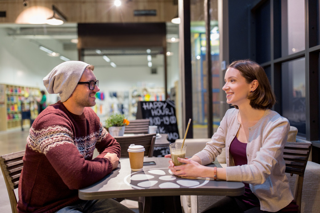 Two students chatting over coffee and a smoothie at a cafe