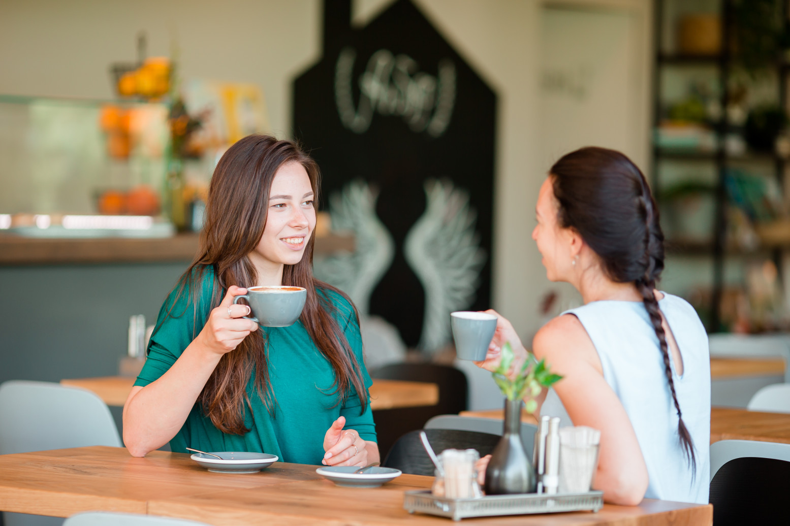 Two young care colleagues sharing coffee and conversation at a cafe