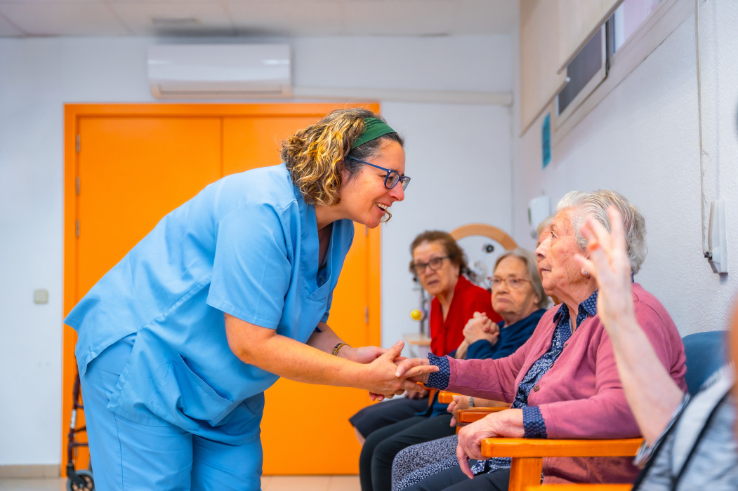A smiling carer greeting seated aged care residents