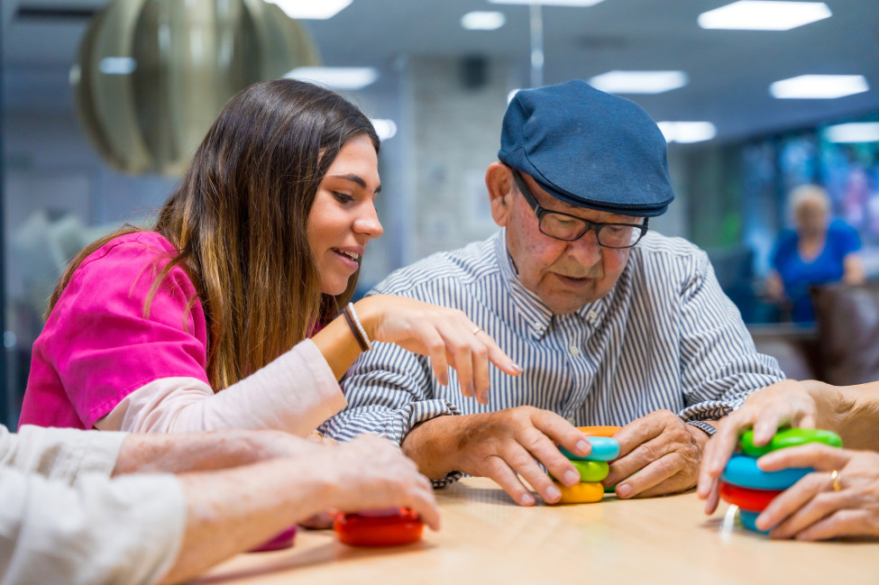 University student volunteer playing a tabletop game with an aged care resident during a weekly companionship visit