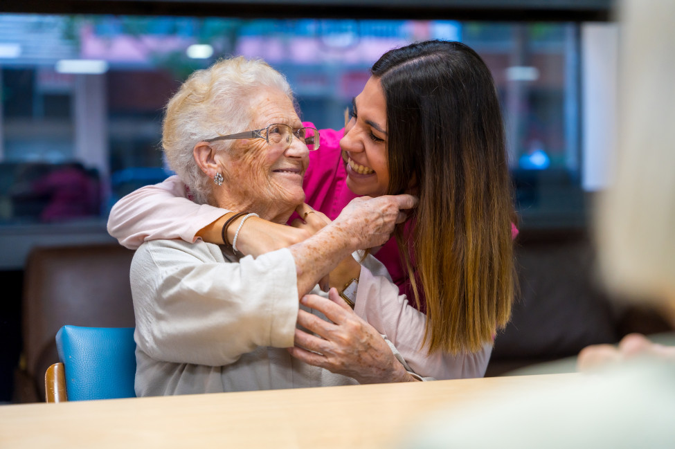 Young volunteer embracing a senior woman - reducing loneliness and social isolation in residential aged care