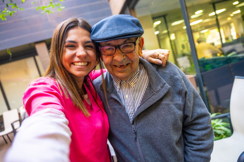 Student volunteer and aged care resident smiling together during a Generations Connect intergenerational visit